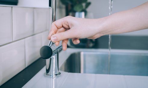 Horizontal shot of a human hand opening the modern sink for the flow of water